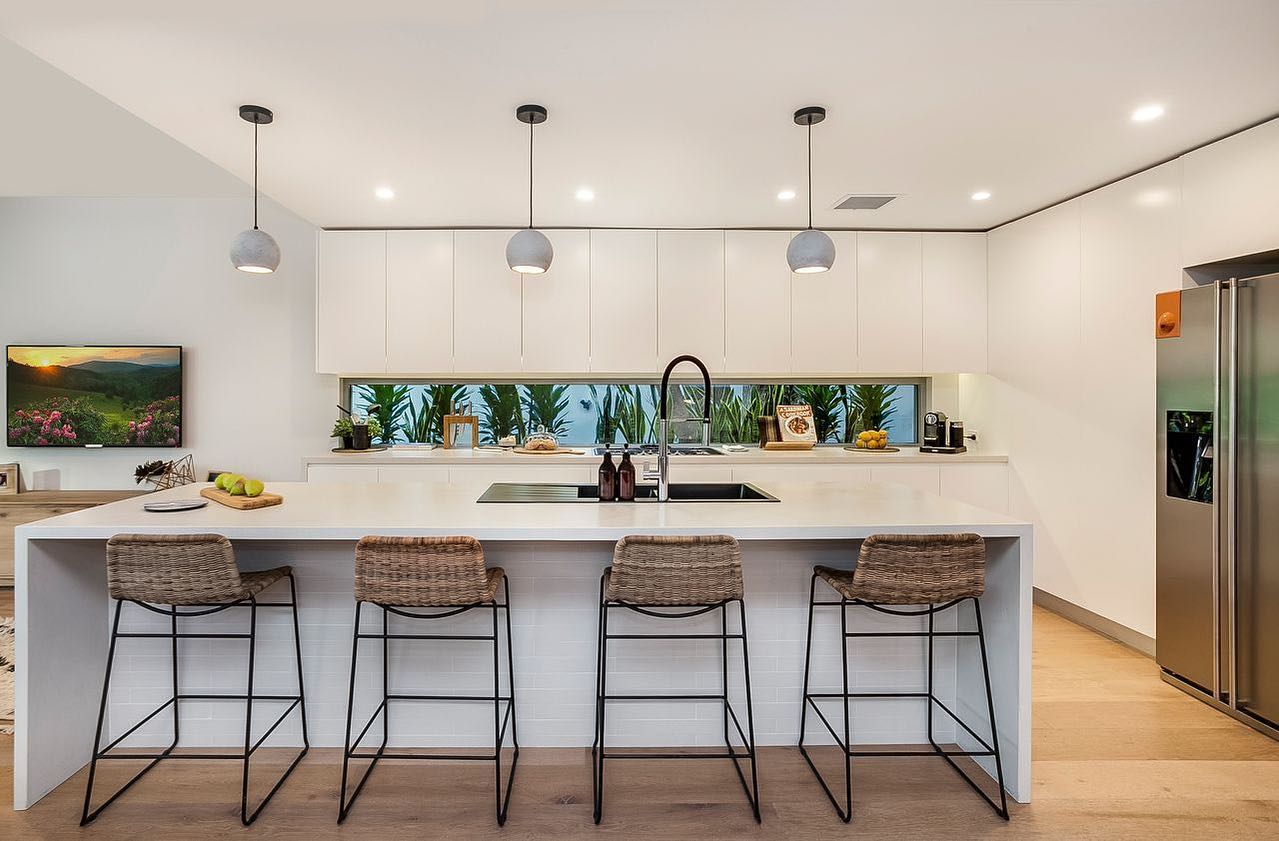 White kitchen with island sink, benchtops and splashback